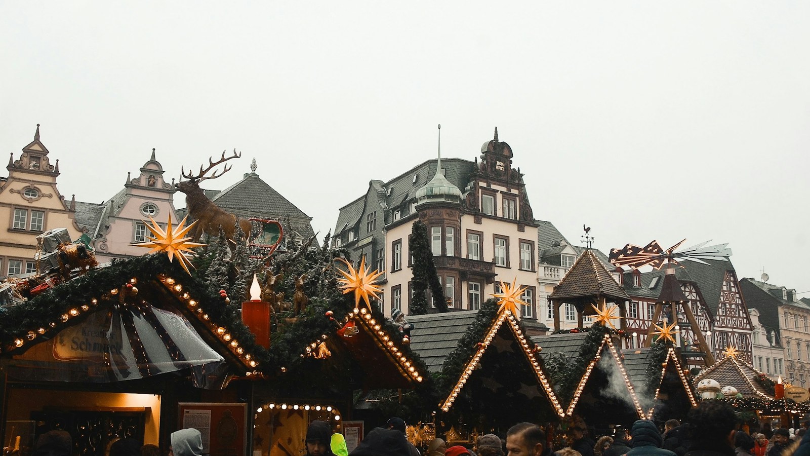 Chalets en bois d'un marché de Noël avec des visiteurs au crépuscule